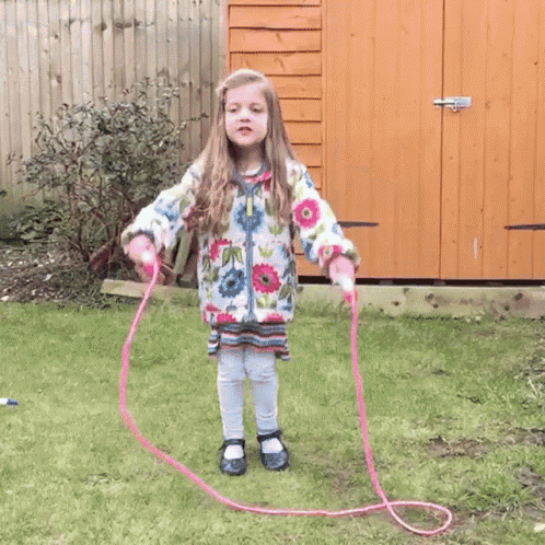 a little girl in a floral jacket jumps in the air