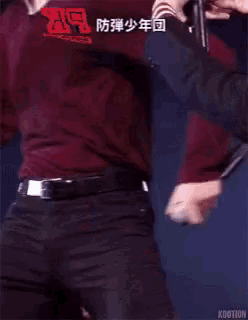 a man in a red shirt is standing on a stage with his hands on his hips