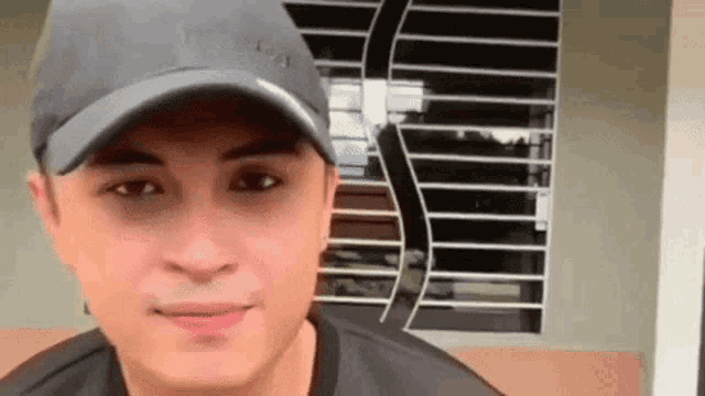 a man wearing a baseball cap and a black shirt is smiling .