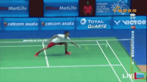 a man is playing badminton on a court with ads for celcom axiata total quartz and victor