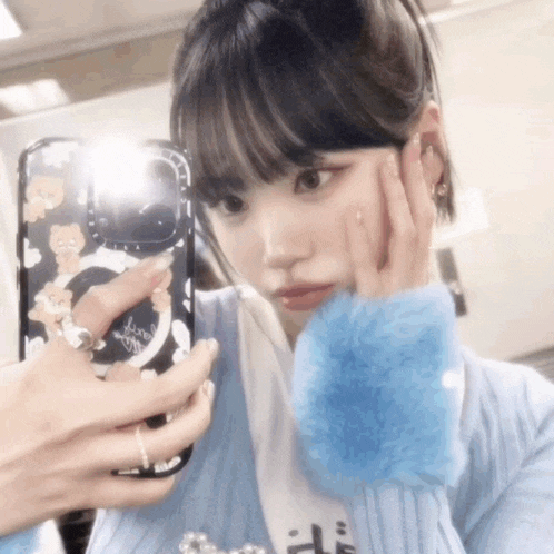 a woman is taking a picture of herself in a mirror with her phone .