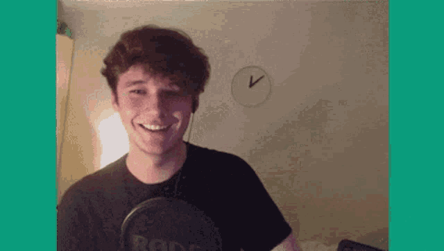 a young man is smiling in front of a rode microphone .