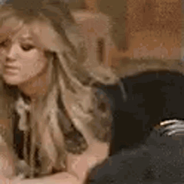 a woman with long blonde hair is sitting on a couch with a man .