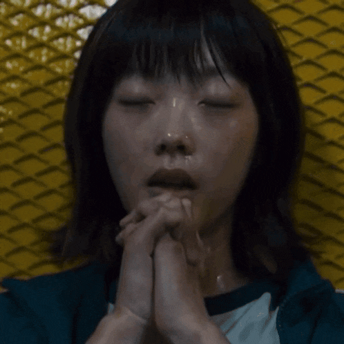 a man in a suit is praying with his hands folded in front of his face