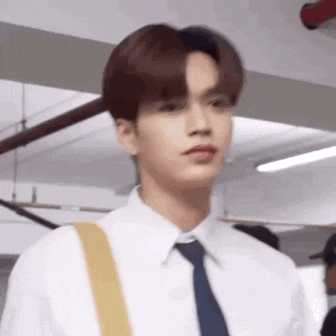 a young man in a white shirt and blue tie is looking at the camera .