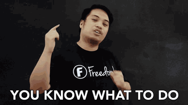 a man wearing a shirt that says freedom is pointing up and says " you know what to do "