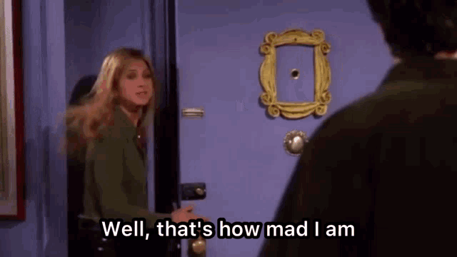 a woman is standing in front of a door with a picture frame on it and talking to a man .