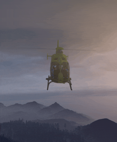 a green helicopter is flying over a mountain landscape