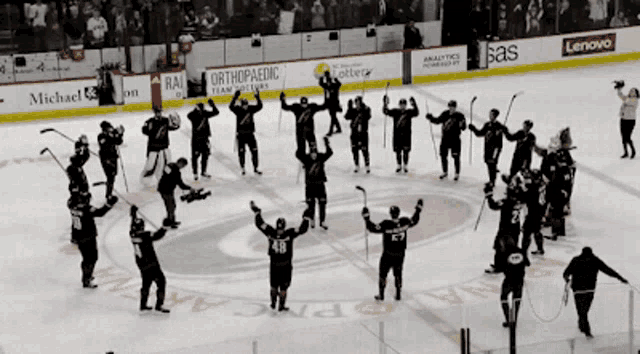 a group of hockey players are standing on the ice in front of an orthopaedic banner