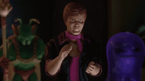 a man in a pink shirt and tie is standing next to a purple monster .