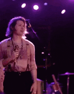 a man is singing into a microphone on a stage in a dark room .