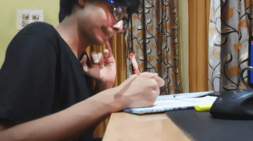 Garoto sentado à escrivaninha estudando, fazendo anotações em um caderno.