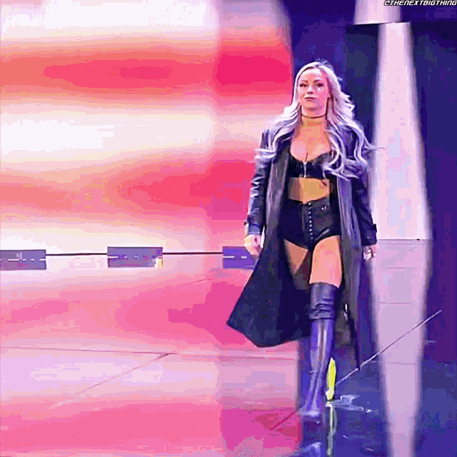 a woman in a trench coat and thigh high boots walks down a runway