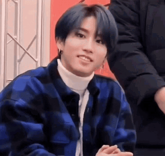 a close up of a person wearing a plaid jacket and a turtleneck .