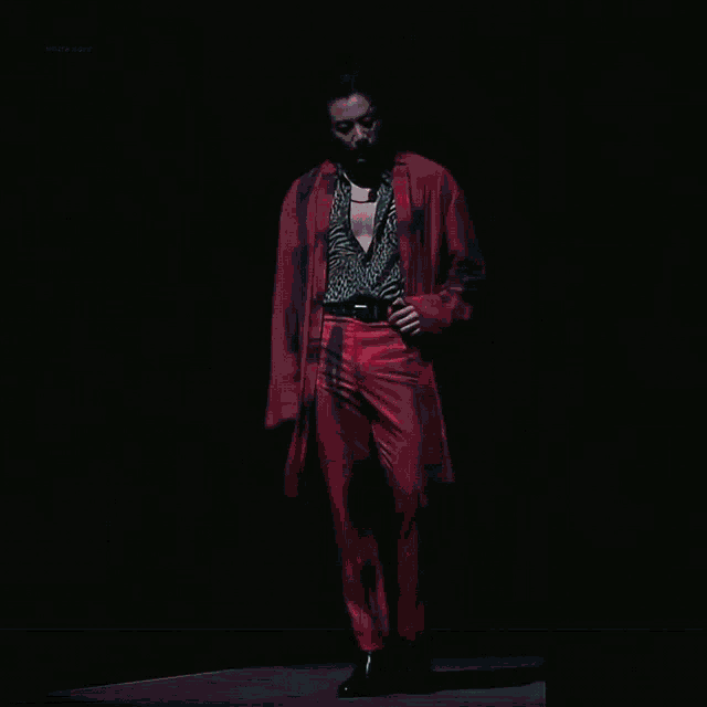 a man in a red jacket and pants is standing in the dark