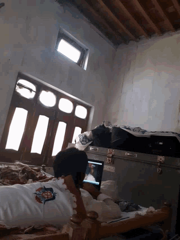 a person laying on a bed with a laptop and a shirt that says ' jesus loves you ' on it