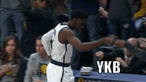 a basketball player shakes hands with a fan while ykb is written on the bottom