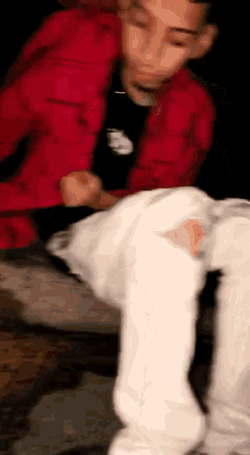 a blurry picture of a man wearing a red jacket and white jeans