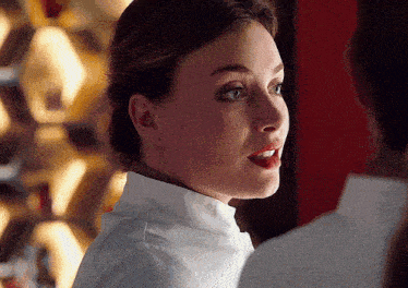 a close up of a woman 's face with a white shirt on