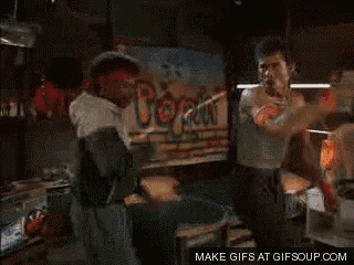 a couple of men are dancing in front of a sign that says booze