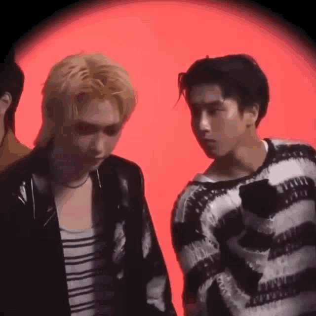 a couple of men are standing next to each other in front of a red background .