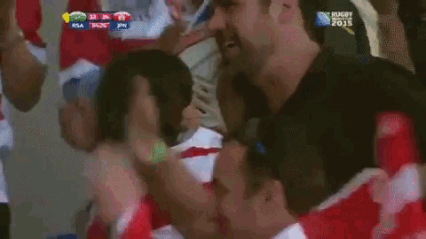a group of people watching a rugby game with a scoreboard that says rugby 2015 at the top