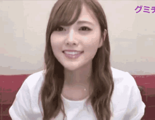 a woman in a white shirt is smiling in front of a wall with purple writing