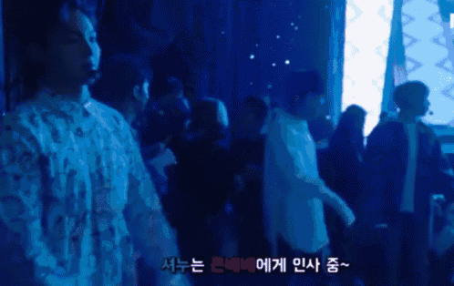 a group of people are standing in a dark room with a blue background