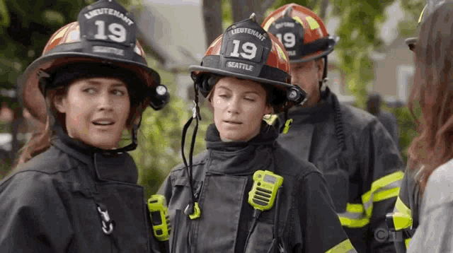 a group of firefighters are standing next to each other and talking to each other .