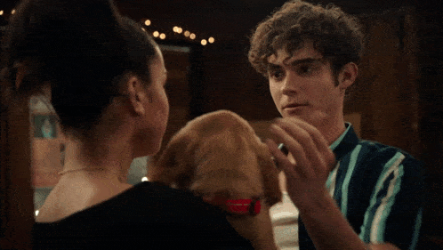 a man and a woman looking at each other while holding a dog