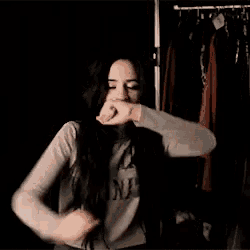a woman with long dark hair is standing in front of a closet and smiling .