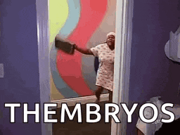 a woman is standing in a doorway with a towel in her hand and the words theembryos written on the wall behind her