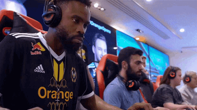 a man wearing headphones and an orange shirt is playing a game