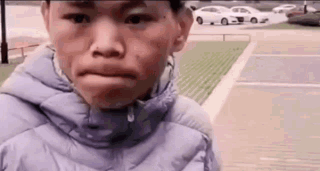 a young boy in a purple jacket is making a funny face .