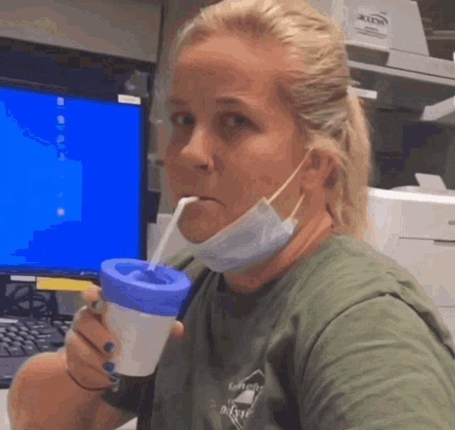 a woman wearing a mask is drinking from a cup