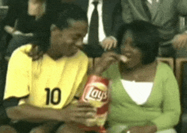 a man wearing a yellow jersey with the number 10 on it is eating a bag of lays chips