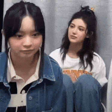 two young girls are sitting next to each other in a room .