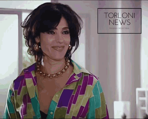 a woman in a colorful shirt is smiling in front of a sign that says torloni news pagina dedicada