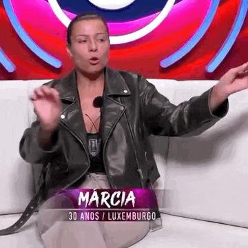a woman is sitting on a couch wearing a leather jacket and making a funny face .