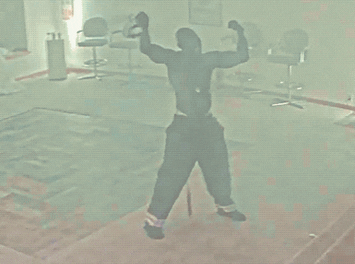 a man flexes his muscles in a room with chairs and a sign that says fire