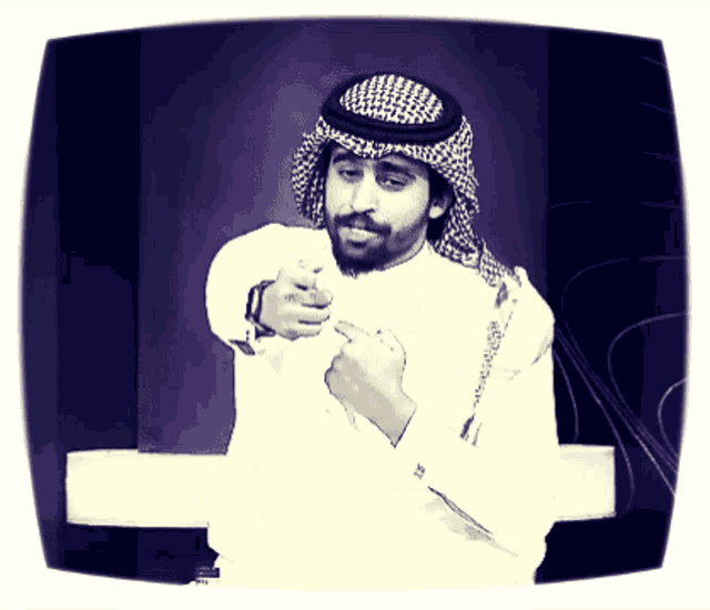 a man wearing a head scarf and a white shirt is pointing