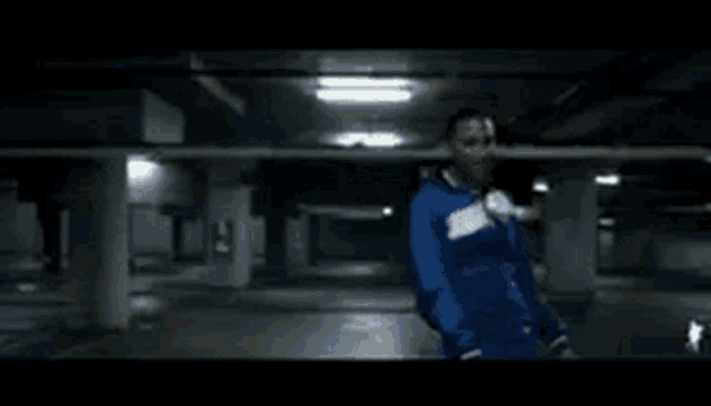 a man is standing in a parking garage wearing a blue jacket .