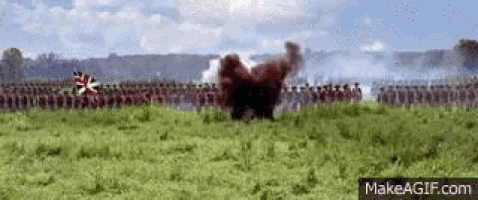 a large group of soldiers are standing in a field with smoke coming out of the ground .