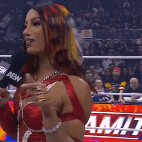 a woman in a red and white wrestling outfit holds a microphone that says aew on it