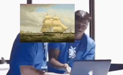 a man sitting in front of a laptop with a picture of a sailboat on his face .