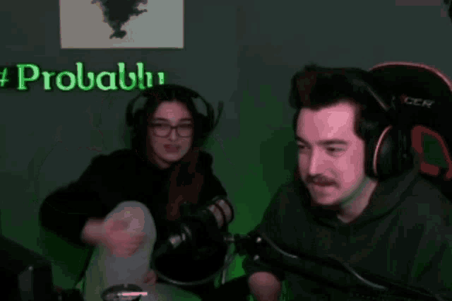a man and a woman are sitting in front of a microphone with a sign that says #probal behind them