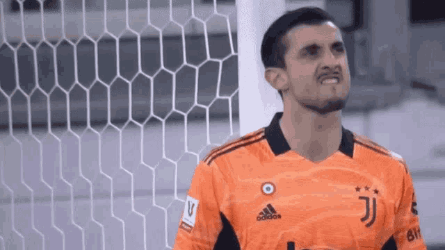 a soccer goalie is standing in front of a soccer net and making a funny face .