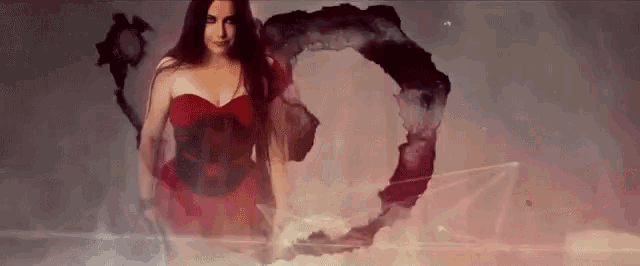 a woman in a red dress is standing in front of a large circle in the sky .