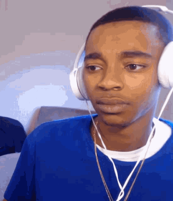 a young man wearing headphones and a blue shirt is looking at the camera