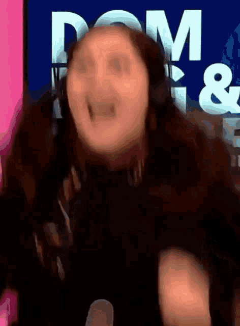 a woman is wearing headphones and making a funny face in front of a sign that says dom &